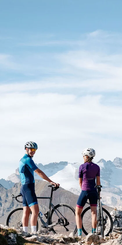 Twee fietsers staan met hun fietsen op een bergpad bij helder weer