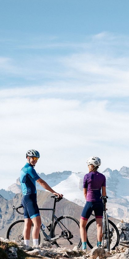 Due ciclisti con le bici su un sentiero di montagna con cielo sereno