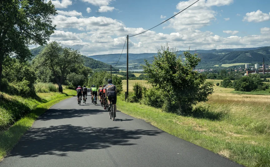 Gruppe von Radfahrern auf Landstraße bei schönem Wetter und Landschaft