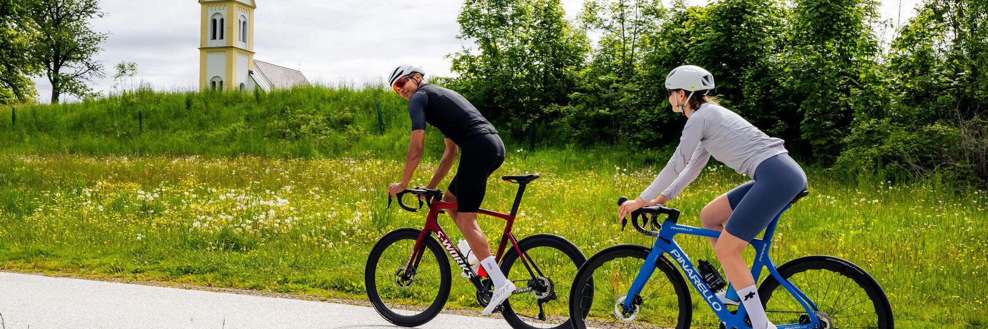 Stift St. Georgen **** © Michael Stabentheiner Zwei Radfahrer fahren auf Landstraße, Kirche und grüne Wiese im Hintergrund
