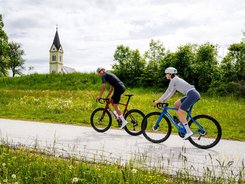 Central Carinthia © Michael Stabentheiner Two cyclists riding on country road with church and green meadow
