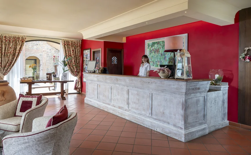 Hotelrezeption mit einer Mitarbeiterin an einem weißen hölzernen Empfangstresen