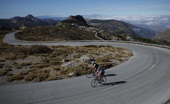 Due ciclisti su una strada di montagna tortuosa con cielo limpido