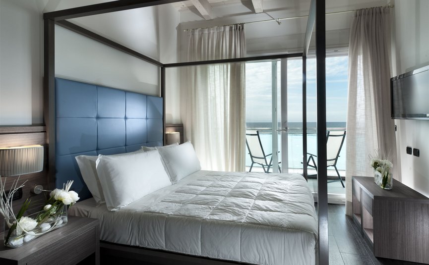 Modern bedroom with canopy bed and balcony overlooking the sea