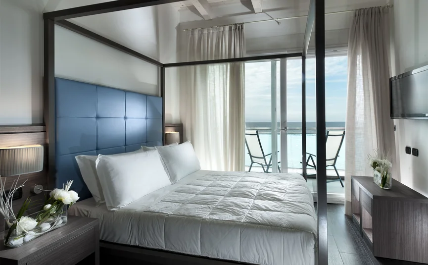 Moderne slaapkamer met hemelbed en balkon met zeezicht