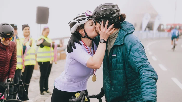 Glocknerkönig 2026 Radfahrerin mit Medaille küsst Person mit Helm und Jacke bei Radrennen