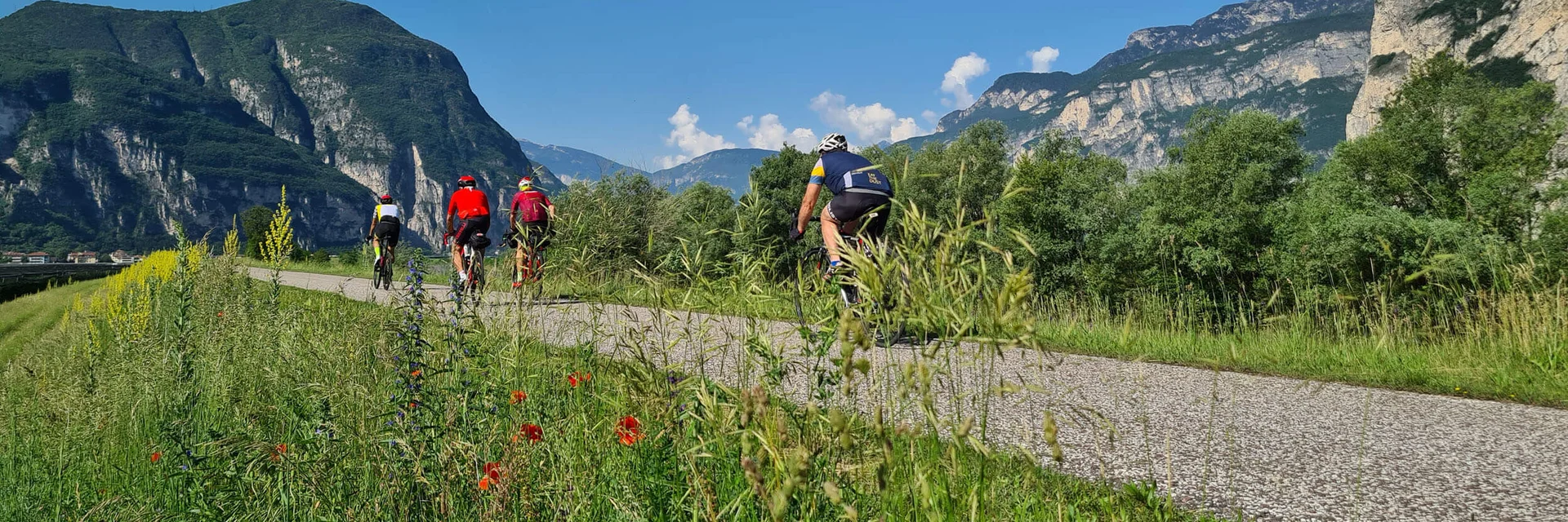 Gruppo di ciclisti su percorso in paesaggio montano con cielo sereno