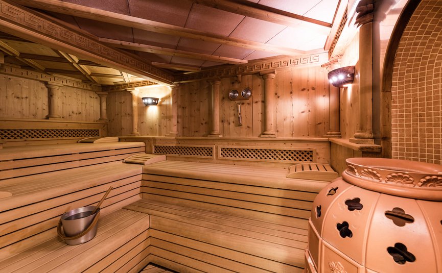 Sauna room with wooden benches and stove in warm lighting