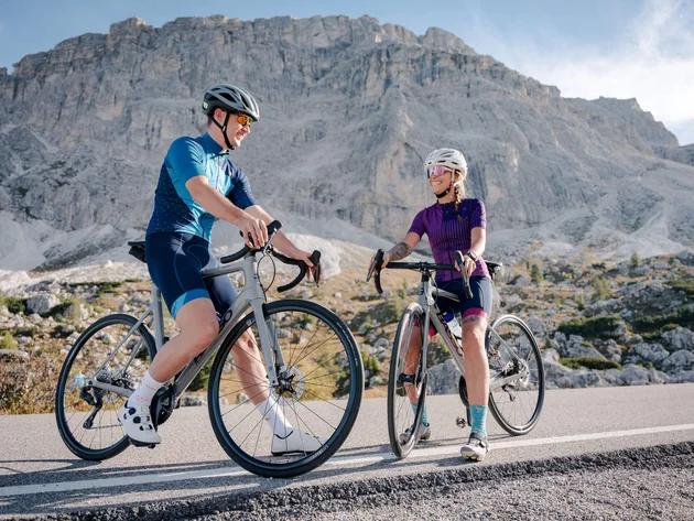 Twee fietsers op een bergweg met rotsachtige bergen op de achtergrond