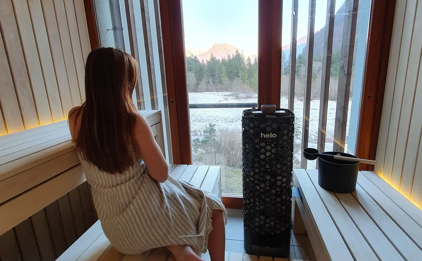 Donna seduta in sauna che guarda fuori dalla finestra paesaggio montano