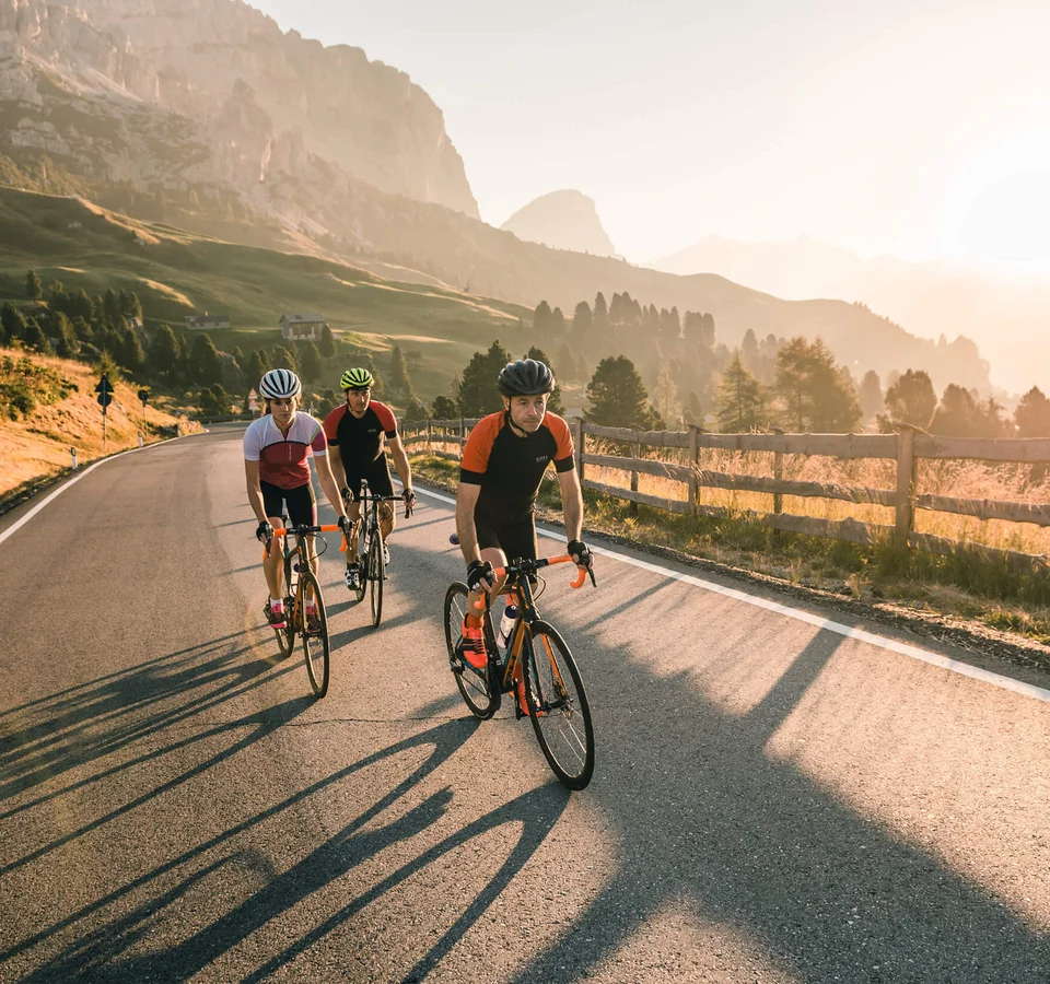 Die schönsten Rennrad-Regionen und Tipps für den Herbst © Molography Drei Radfahrer auf Bergstraße im Sonnenlicht