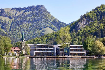 Modern buildings by lake with forested mountains and church steeple