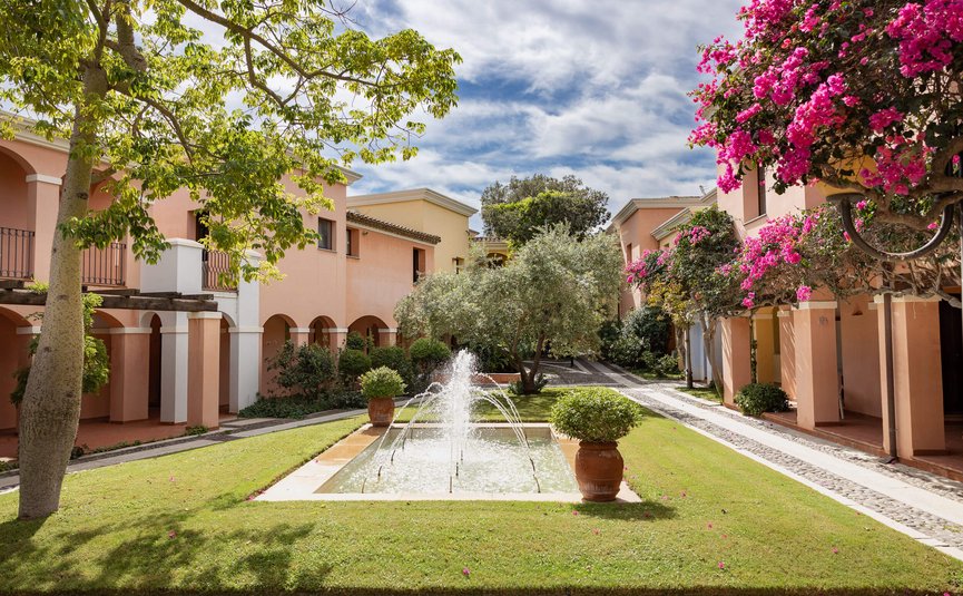Courtyard with fountain, trees, and Mediterranean-style buildings