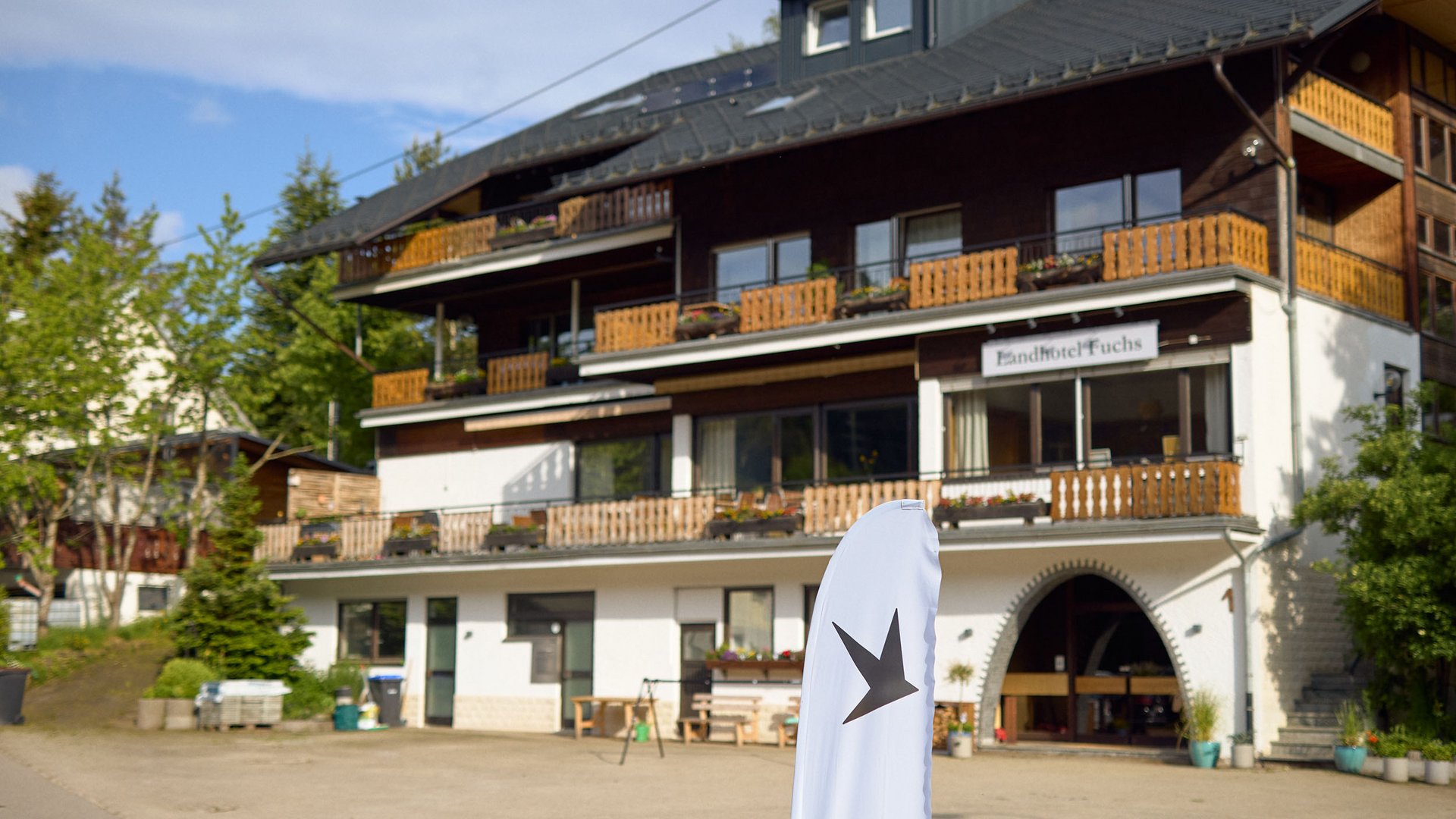 Außenansicht Landhotel Fuchs mit Balkonen und Fahne im Vordergrund