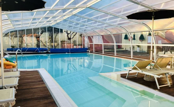 Frühling & Herbst Special: Dein perfekter Radurlaub © Villa Giada spEace & Bike Resort Überdachtes Schwimmbad mit Liegestühlen und Sonnenschirmen