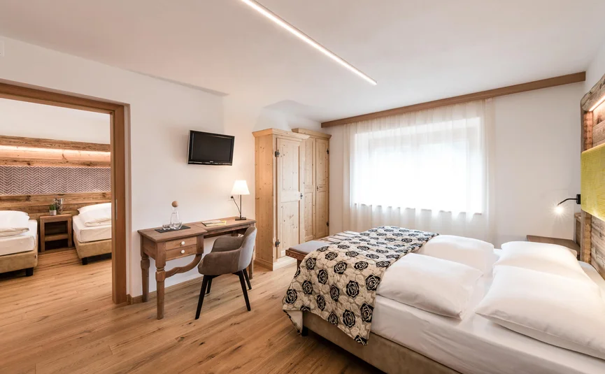 Helle Hotelzimmer mit Doppel- und Einzelbetten, Holzmöbeln und modernem Design