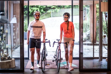 Twee fietsers met helmen en fietsen binnen in een modern gebouw