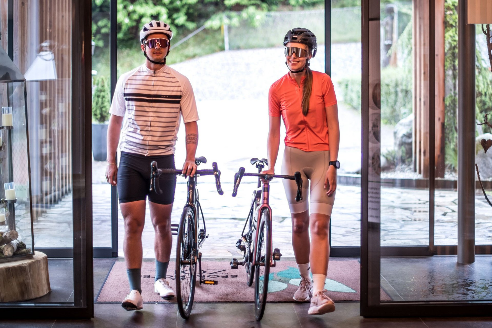 Twee fietsers met helmen en fietsen binnen in een modern gebouw