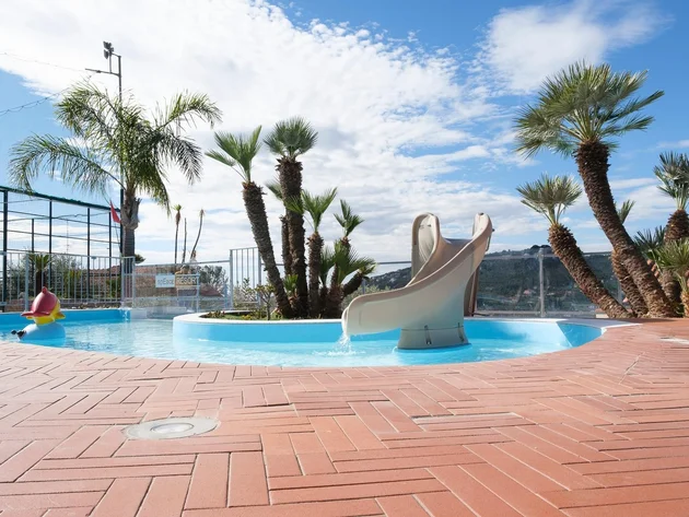 Villa Giada SpEace Resort: Mit deinem Rennrad aufs Zimmer © Villa Giada spEace & Bike Resort Kleiner Pool mit Rutsche und Palmen auf einer Terrasse bei sonnigem Himmel