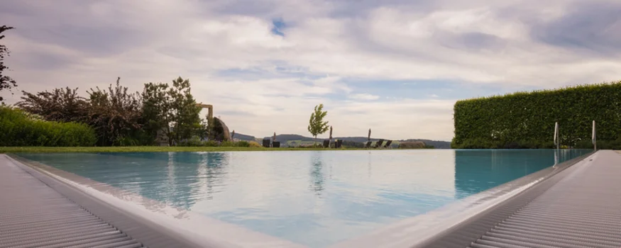 Blick auf einen ruhigen Pool mit Landschaft und bewölktem Himmel im Hintergrund