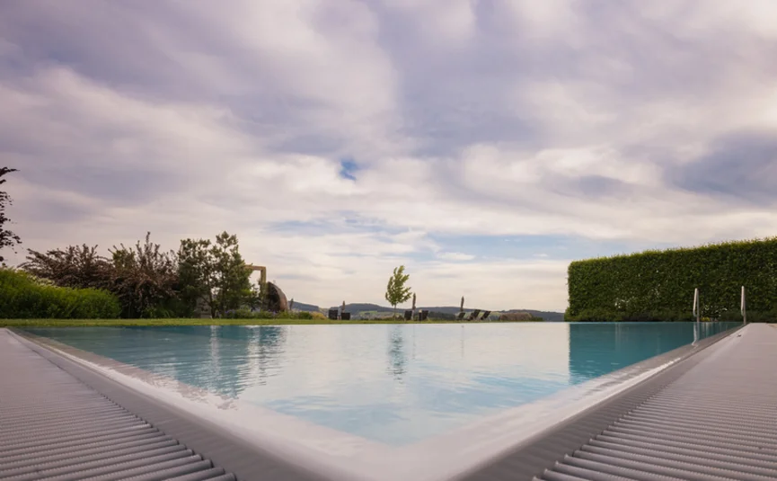 Blick auf einen ruhigen Pool mit Landschaft und bewölktem Himmel im Hintergrund