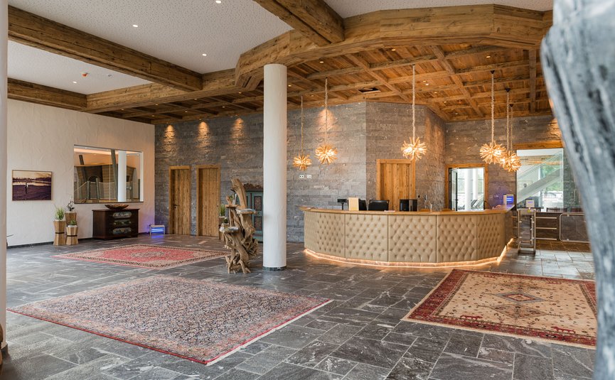 Hotel reception with rustic wooden ceiling and decorative rugs on stone floor