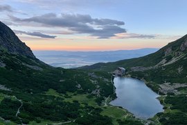 Lago di montagna e rifugio circondati da colline verdi al tramonto