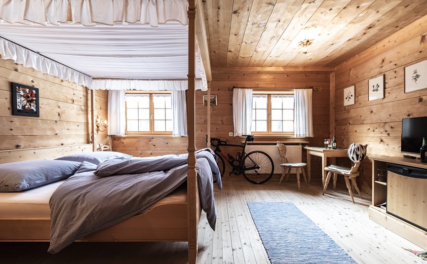 Gemütliches Holzschlafzimmer mit Bike, Tisch und Betten mit blauem Bettzeug