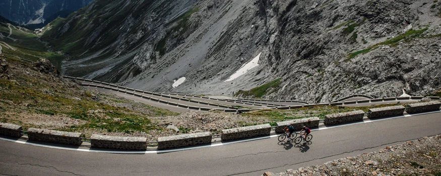 Zwei Radfahrer auf einer kurvenreichen Bergstraße in den Alpen