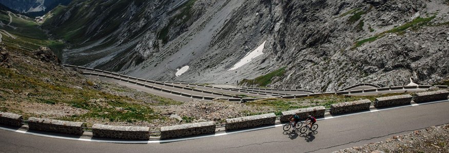 Zwei Radfahrer auf einer kurvenreichen Bergstraße in den Alpen