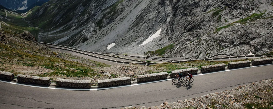 Zwei Radfahrer auf einer kurvenreichen Bergstraße in den Alpen