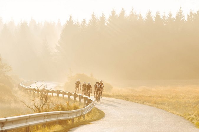 Gruppe von Radfahrern auf geschwungener Straße im Sonnenlicht