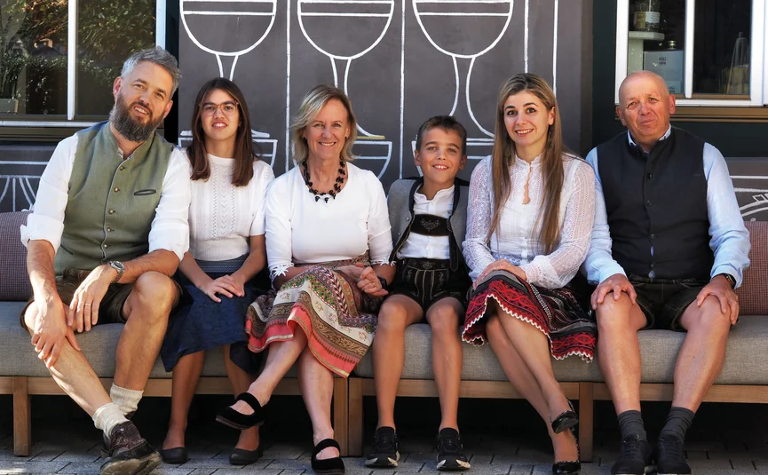 Familie in traditionele kleding buiten op een bank