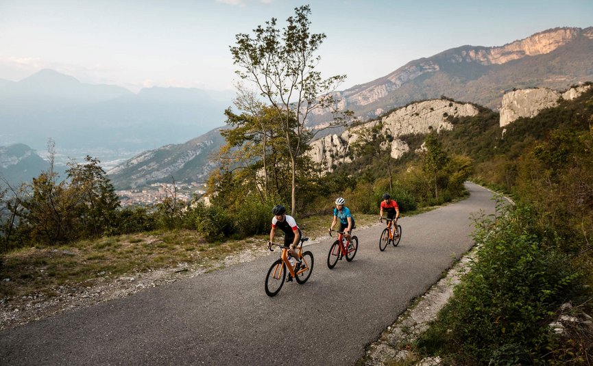Tre ciclisti su strada di montagna con colline rocciose sullo sfondo