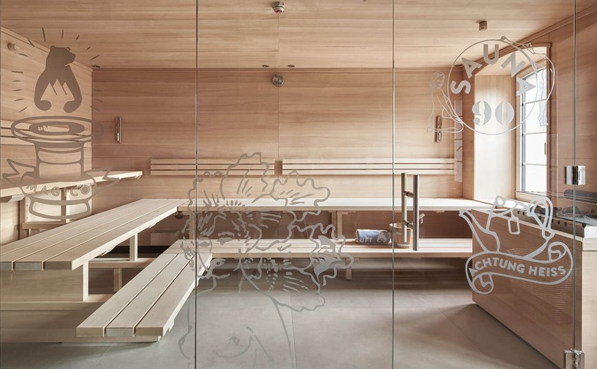 Sauna room with wooden benches and glass door with sauna decals
