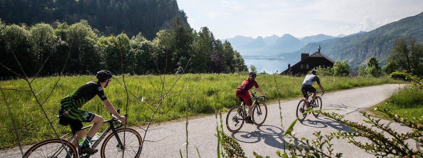 Three cyclists on a country road in a mountainous landscape on a sunny day