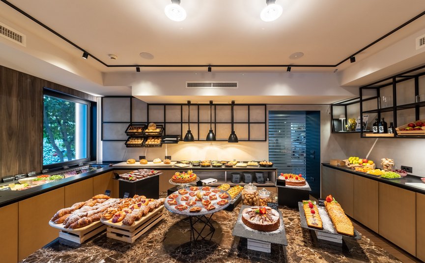 Buffet mit verschiedenen Broten, Kuchen und Obst in modernem Raum