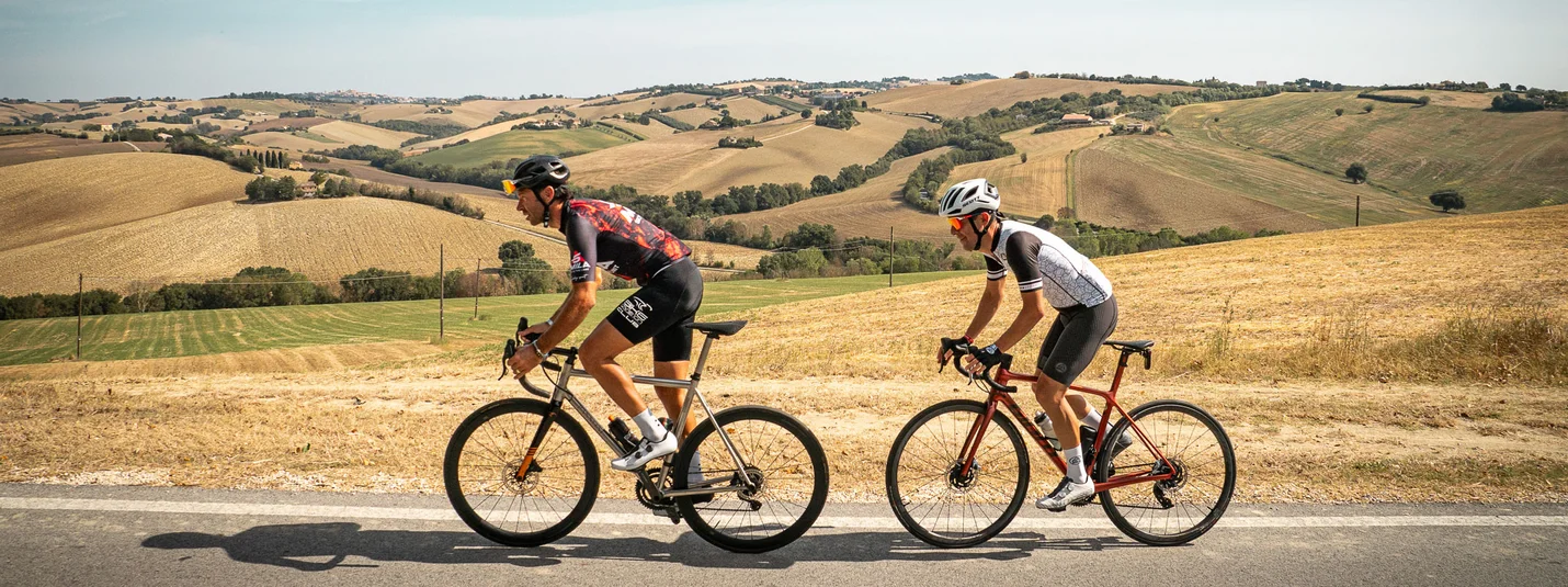 Direkt bis zum Monte Conero © Alain Rumpf Zwei Radfahrer fahren auf Landstraße durch hügelige Landschaft.
