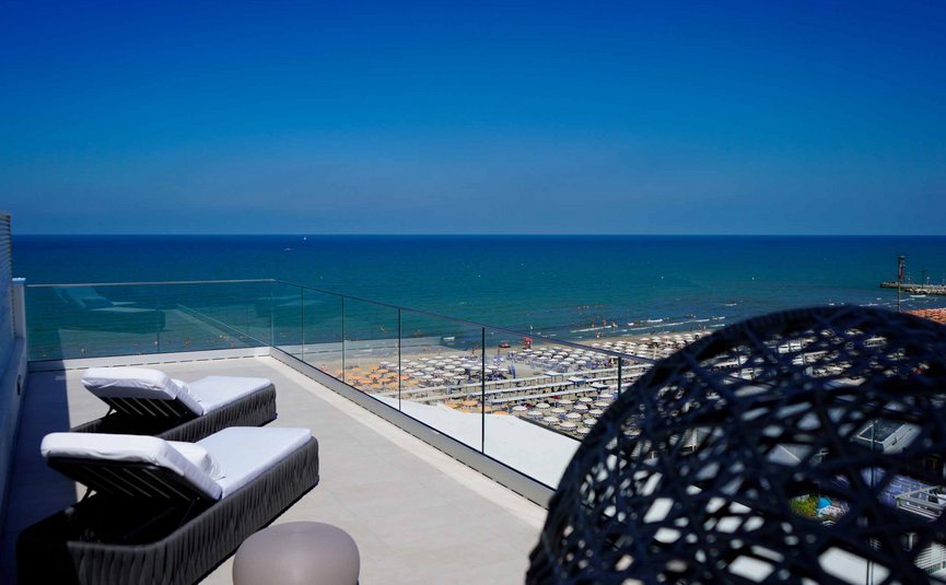 Due sdraio con vista sul mare e spiaggia affollata sotto il cielo blu