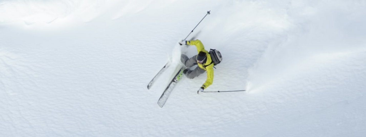 Skieën in gele jas door verse poedersneeuw