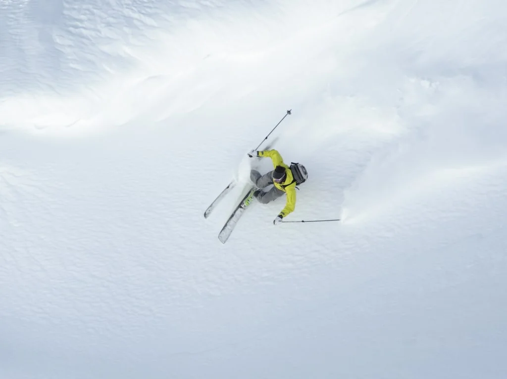 Skieën in gele jas door verse poedersneeuw