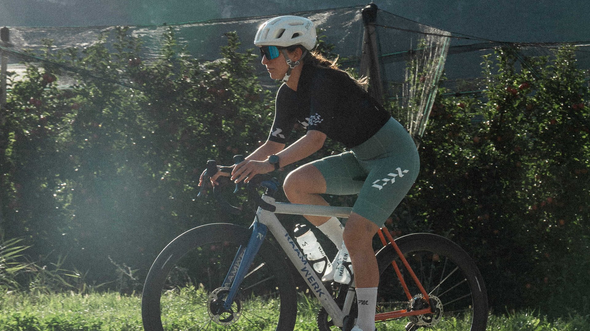 Frau fährt Rennrad bei sonnigem Wetter vor Bergkulisse