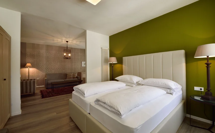 Camera da letto moderna con letto matrimoniale, parete verde e soggiorno adiacente