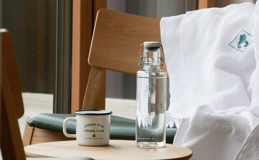 Waterfles en mok op houten tafel naast stoel met badjas