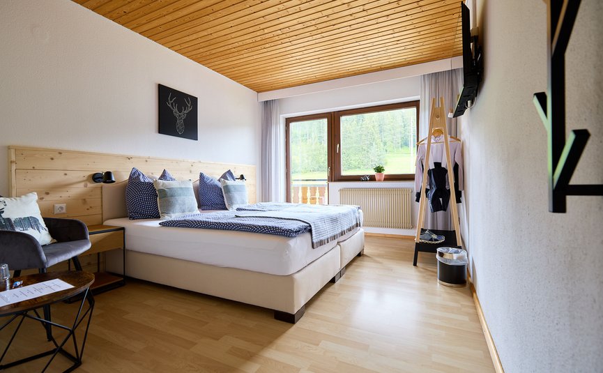 Gemütliches Hotelzimmer mit Holzdecke und Bergblick