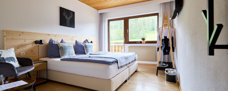 Gemütliches Hotelzimmer mit Holzdecke und Bergblick