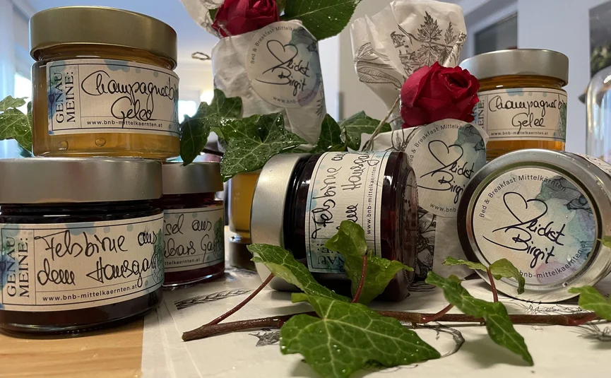 Several jars of homemade jam and jelly decorated with red roses and ivy