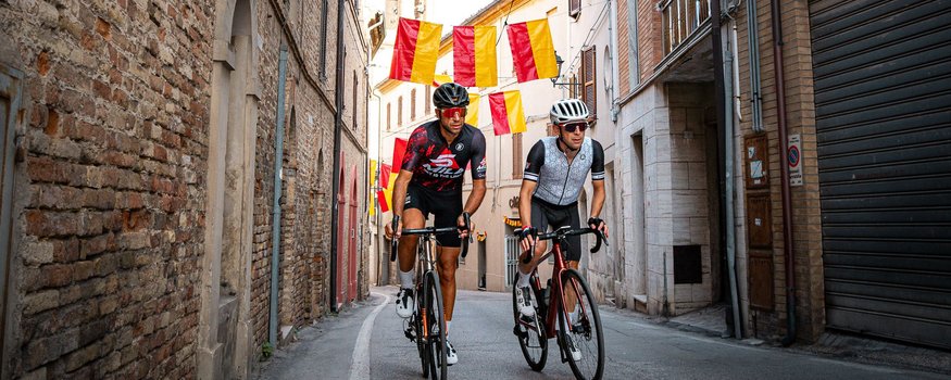 Natural Village Resort **** © Alain Rumpf Zwei Radfahrer fahren durch eine Gasse mit rot-gelben Fahnen