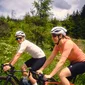 Twee wielrenners fietsen op een weg met groene omgeving op de achtergrond