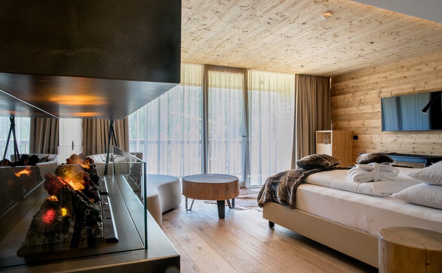 Modernes Schlafzimmer mit Kamin, großen Fenstern und Holzwänden